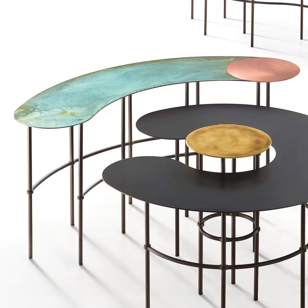 Scribble table behind a semi-circular black table with a golden circle in the center on top of a white floor