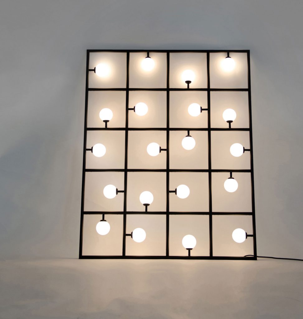 Square lights with the yellow bulbs illuminated in front of a darkly lit room with a grey wall behind