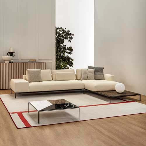 Cream colored Dizzy sofa on top of a cream colored rug with wooden floors and white walls surrounding the sofa