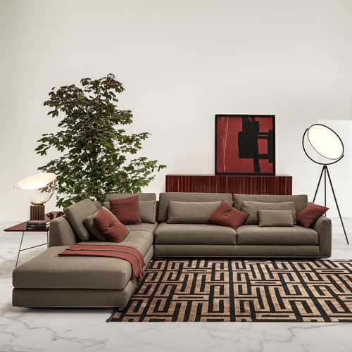 Ellington in a brown color with red pillows on top and on top of a brown maze patterned rug