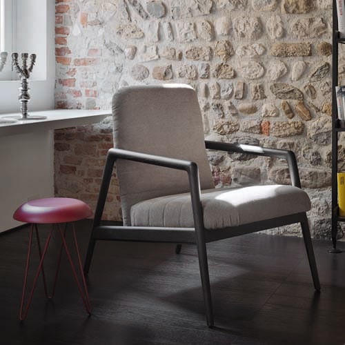 Carnaby chair in a cream color on a dark wooden floor with a window and stoned wall in the background