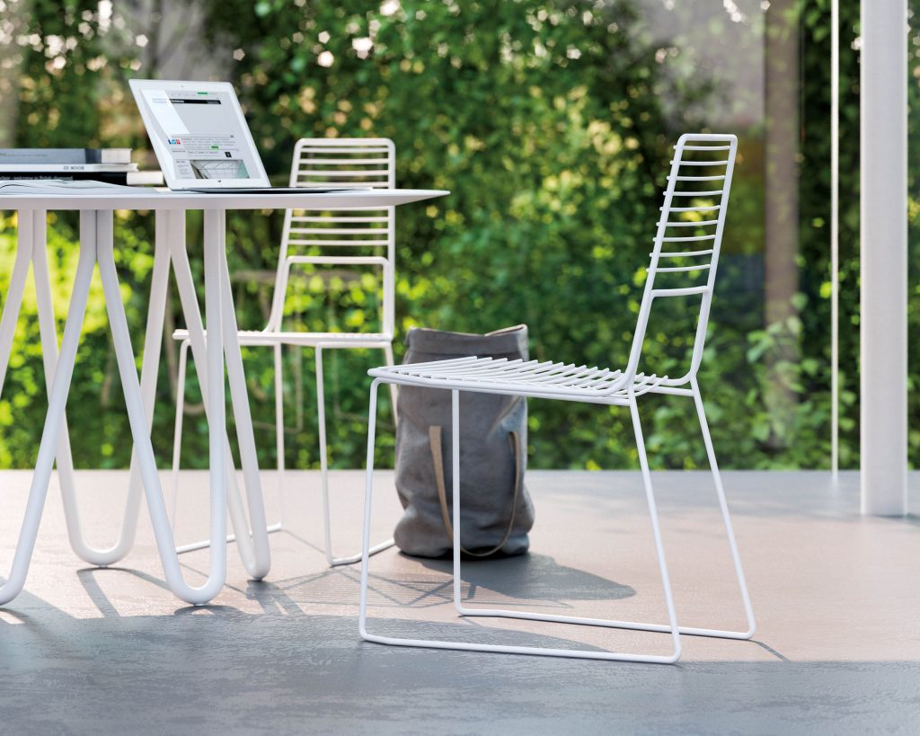 Alieno Peacock in white with narrow backrests in front of a table on a patio