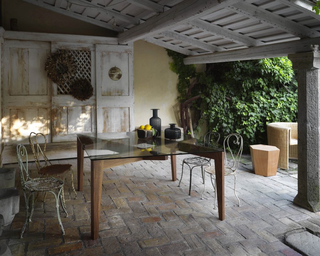 Autoreggente on a wooden floor with a chair in front of it and a yellow wall with plants on the side in the background