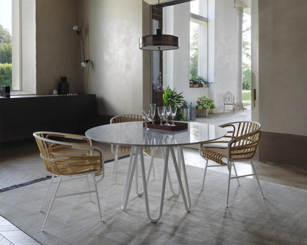 Meduse surrounded by woven chairs on a grey carpet