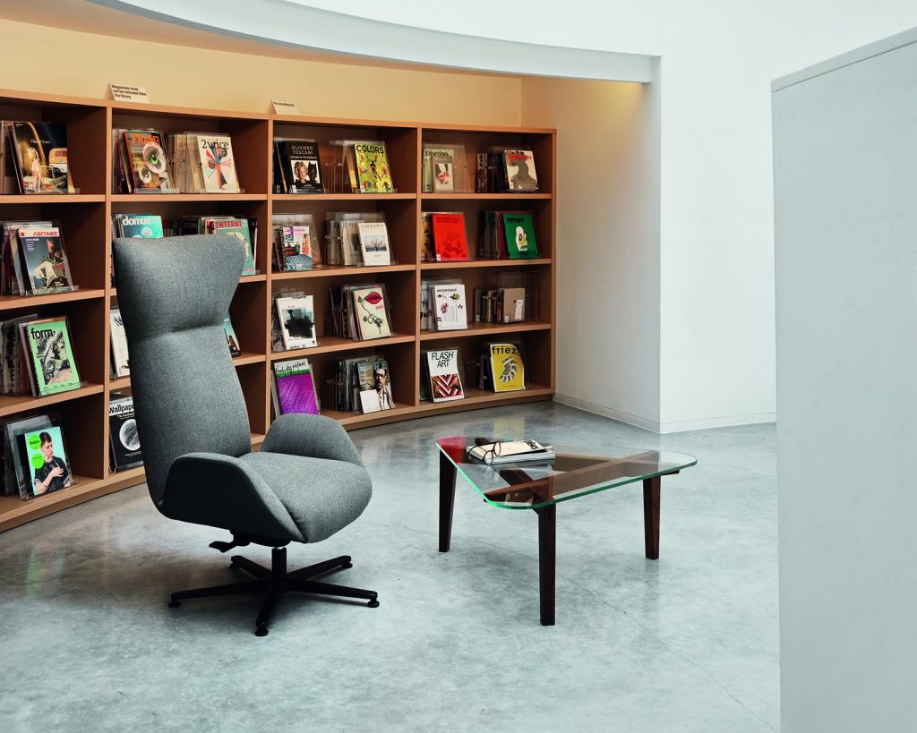 Soho chair in grey with a glass coffee table in front and a library bookcase behind