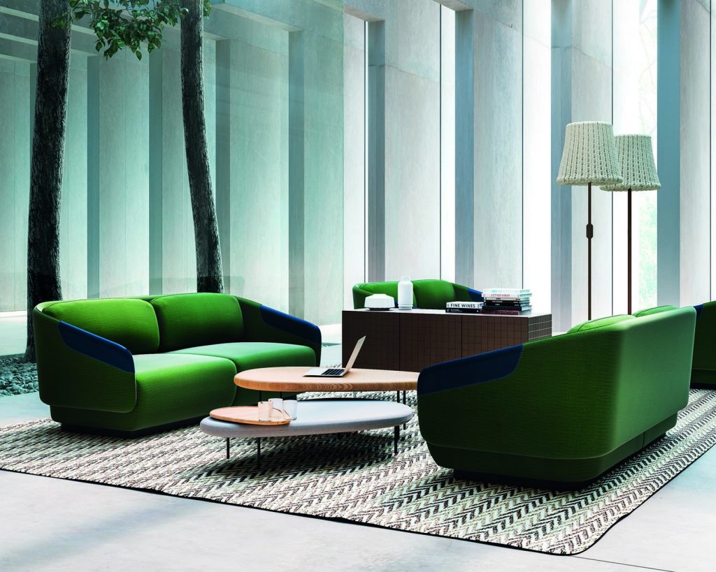 Side angle Worn green couches facing each other with tables between the couches