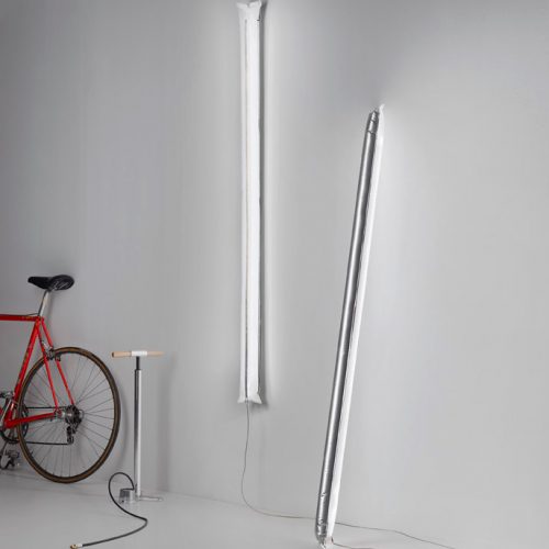 A bike parked next to a white wall with Blow Me Up lights hanging on a wall in a room