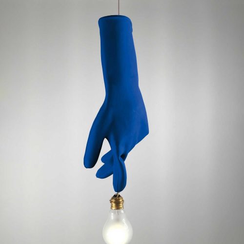 Luzy in blue illuminated hanging from a ceiling in front of a white wall
