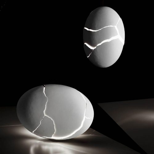 Two Broken Egg lights on top of a table. One is vertically hanging over the table and the other horizontally lying on the table