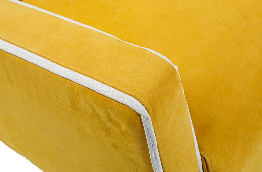 Close up of Capri armrest in yellow leather in front of a white background