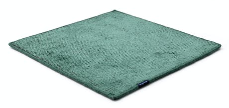 Handmade rug made of fine wool and fabrics in a green tone on a white background