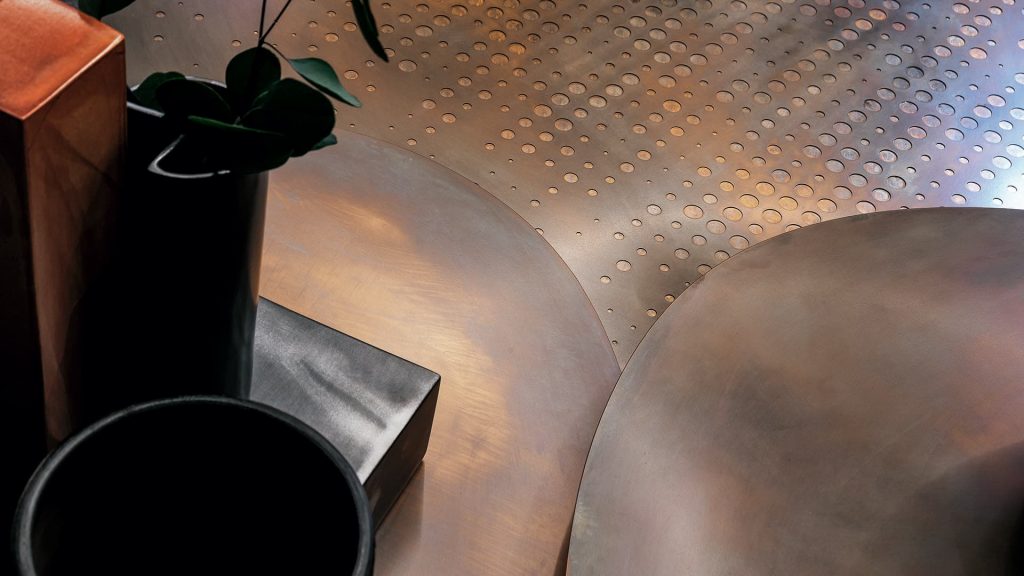 Coseup of Galaxy table with three round giratory tables made of metal and brass on a black background.