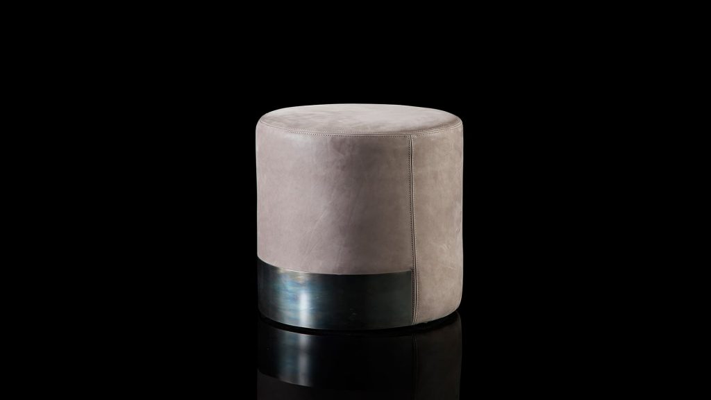 Gelly Pouf upholstered in pink leather and a base in black steel on a black background.