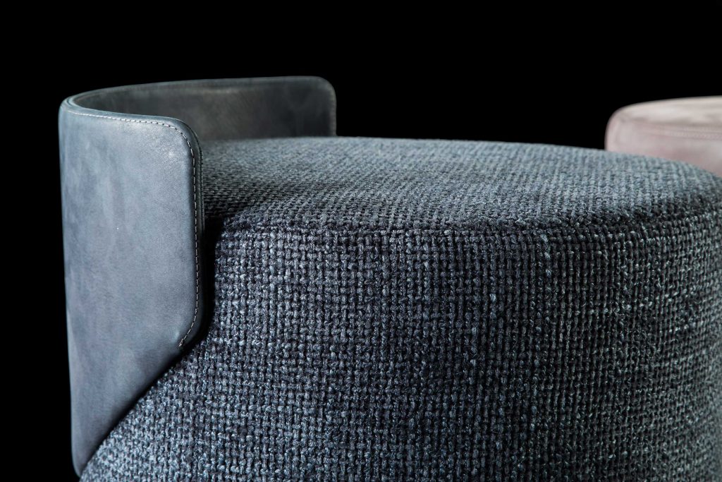 Closeup of Gelly Pouf upholstered in gray leather on a black background.
