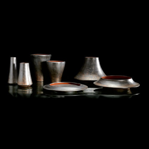 Seven H Vases. Red color inside, silver outside color. One long spool vase, one small spool vase, one medium bowl, one long bowl, one small spool vase, long spool vase on a black background.