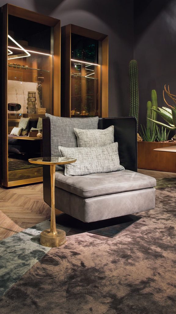 Human Armchair upholstered in brown leather and three gray cushions. Structure armchair with metal base frame and central leg in a living room.