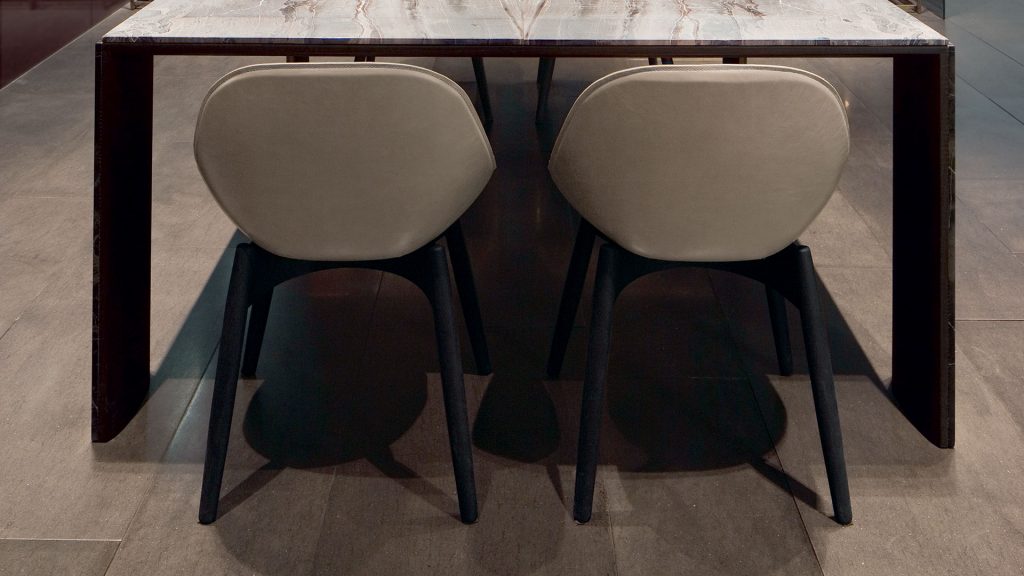 Two Dining June Chairs, base and four legs in natural wood, cover in brown leather in a dining room.