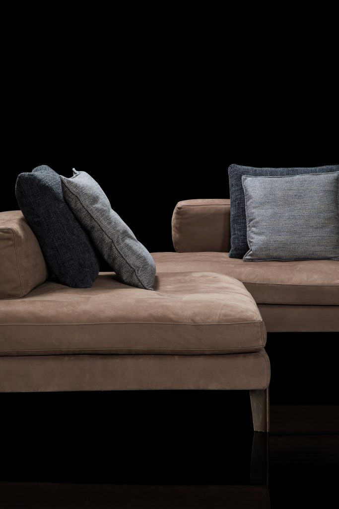 sofa in the shape of the el made of velvet and steel base on a black background