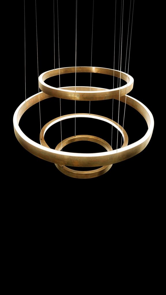 LED Pendant Light Ring made up of four brass rings using suspension wires on a black background.