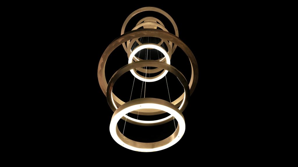 LED Pendant Light Ring made up of four brass rings using suspension wires on a black background.