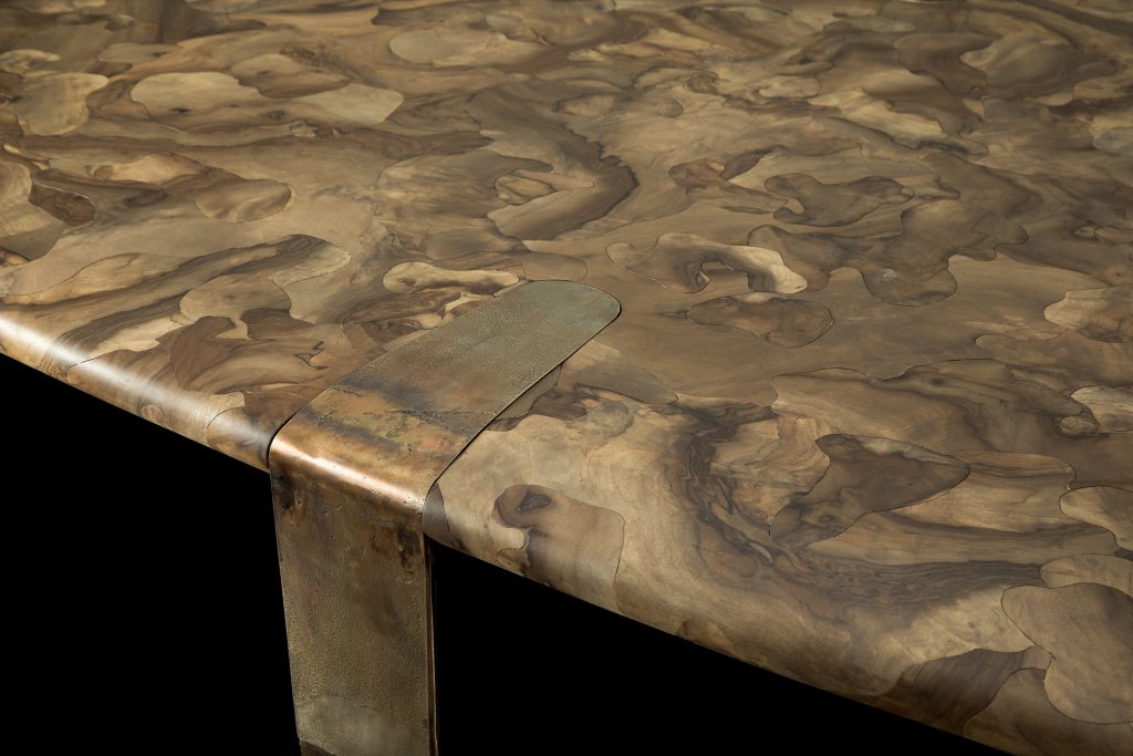 Closeup of Oxymoron Table Structure steel frame with four legs in sandcasting, bronze. Top in natural solidwood on a black background.