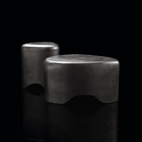 Two Pebble Tables made from black stoneware with triangle like shape on a bkack background.