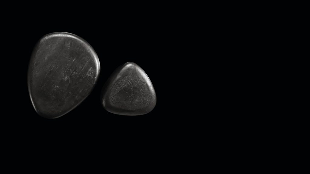 Two Pebble Tables made from black stoneware with triangle like shape on a bkack background.