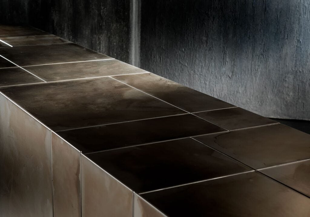 Slim Side High sideboard. Structure, base and four doors, finish in titanio on a black background.