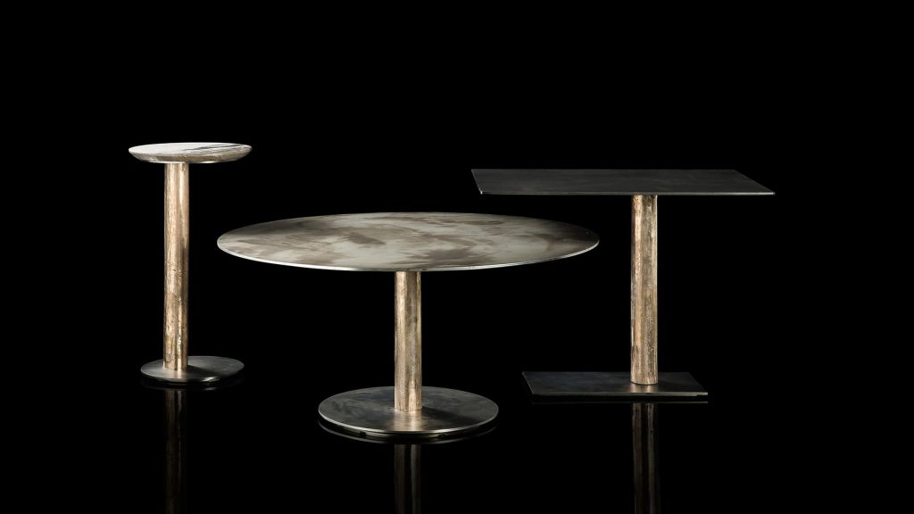 Three Twistable Coffe Table And Consolles. Black structure support, platinum central leg and a top in gray and white stone, one in silver and the other in black on a black background.