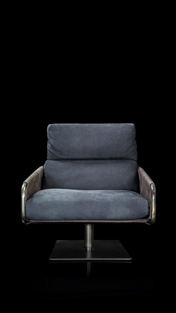 Voyage armchair, curved bronze steel structure with brown leather, gray leather cushion upholstery, central black steel leg on a black background.