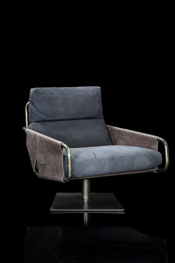 Voyage armchair, curved bronze steel structure with brown leather, gray leather cushion upholstery, central black steel leg on a black background.