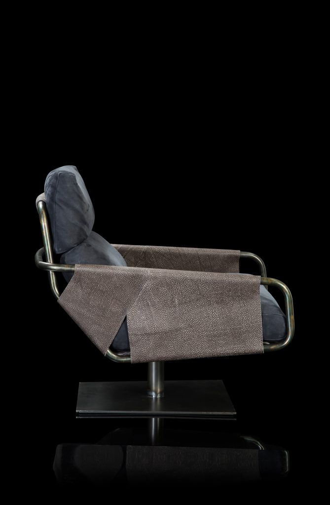 Voyage armchair, curved bronze steel structure with brown leather, gray leather cushion upholstery, central black steel leg on a black background.