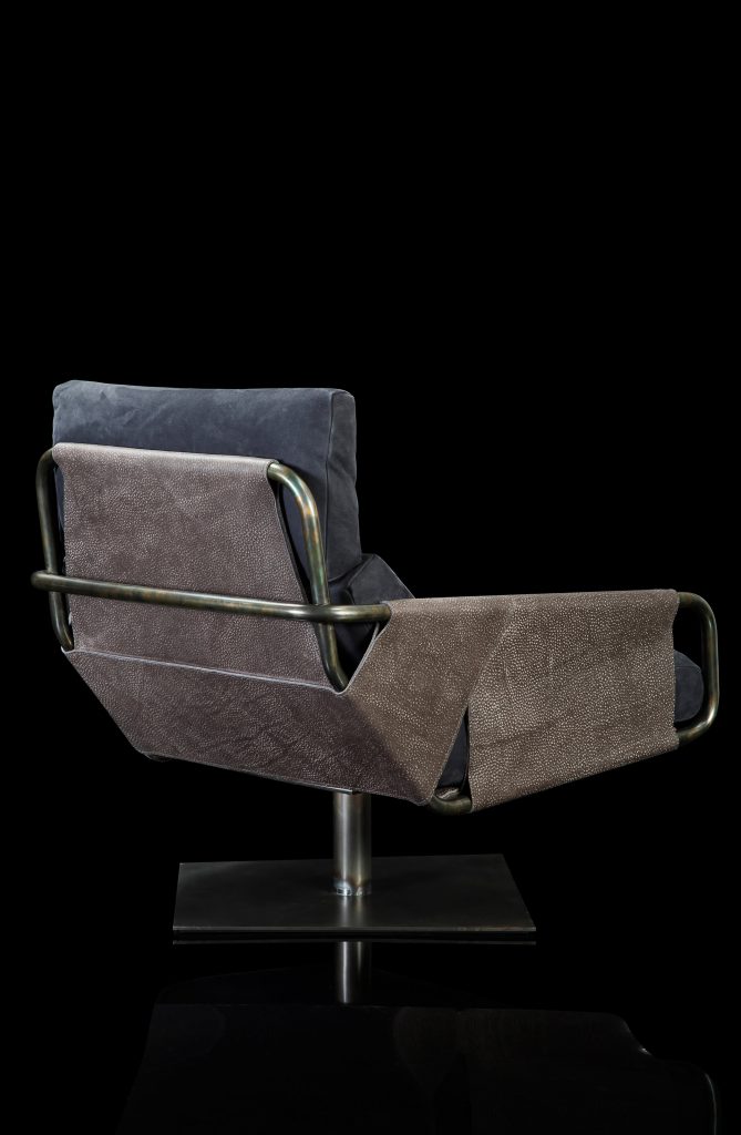 Voyage armchair, curved bronze steel structure with brown leather, gray leather cushion upholstery, central black steel leg on a black background.