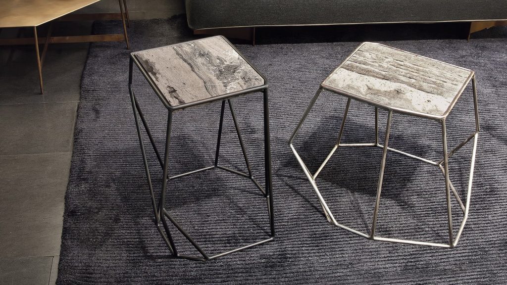 Two W Tables, structure in rod metal diamond like shape, left in black and right in bronze. Top in white and gray marble in a living room.