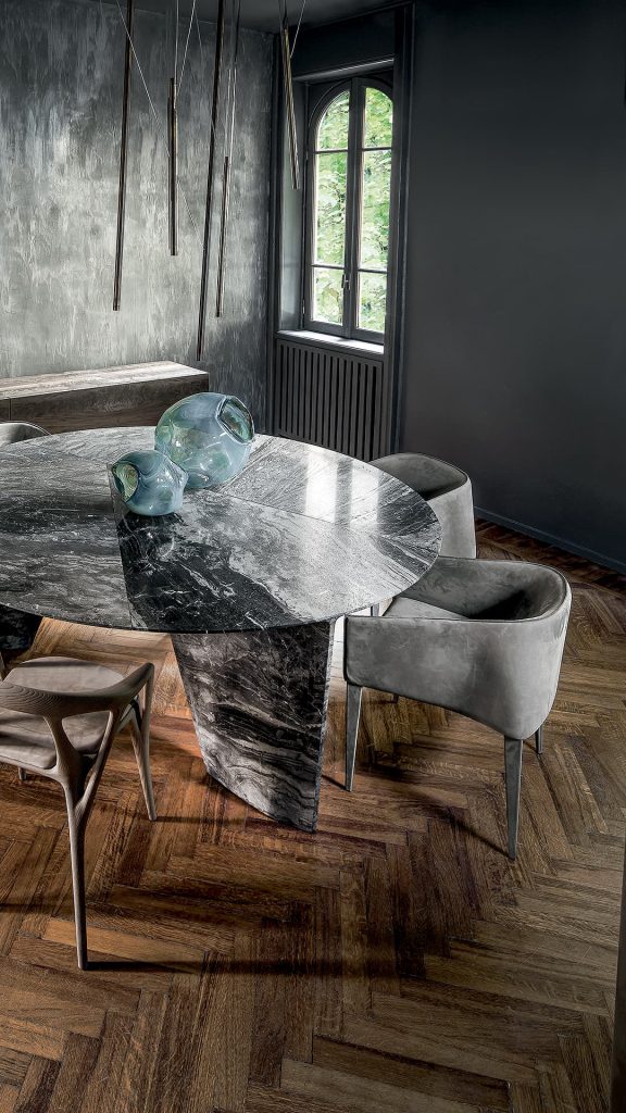 Four Zagg Chairs, upholstered in gray fabric and four legs in silver steel in a dining room.