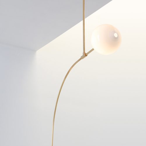 suspended lamp with an illuminated white sphere and golden base.