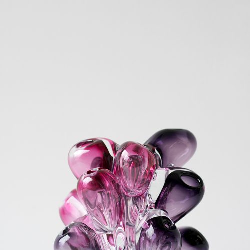 organic glass sculpture of multiple purple shapes on a white background.