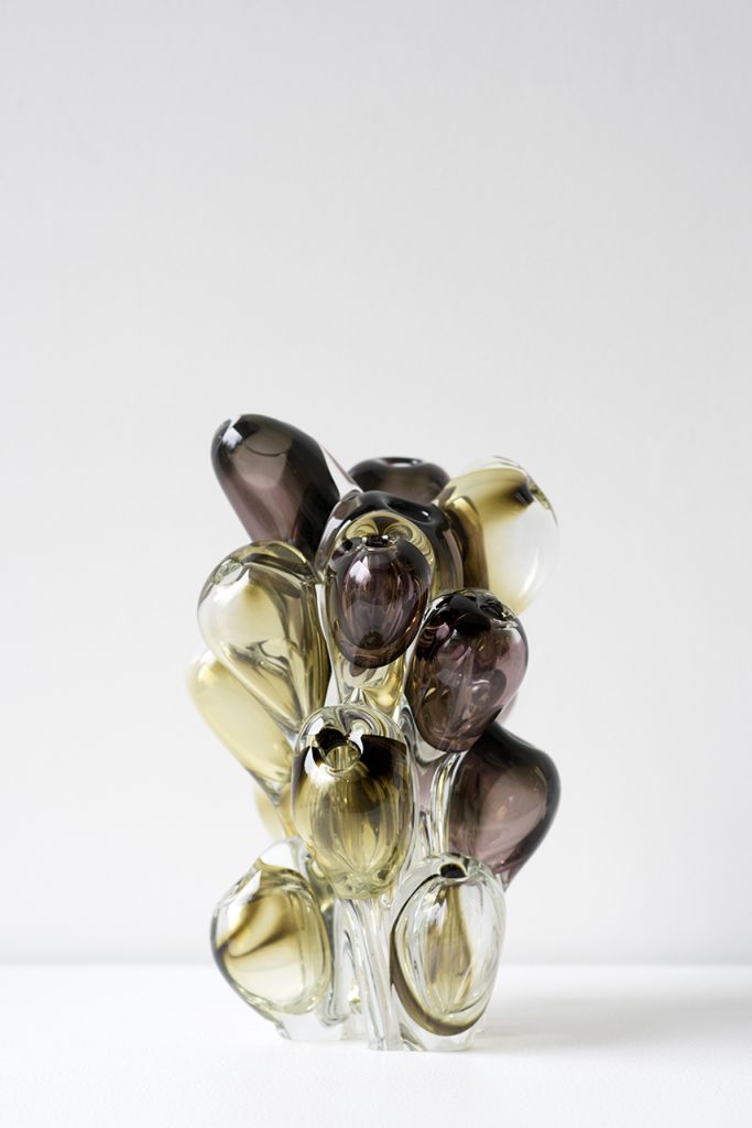 glass sculpture in multiple shapes in gold and black on a white background.
