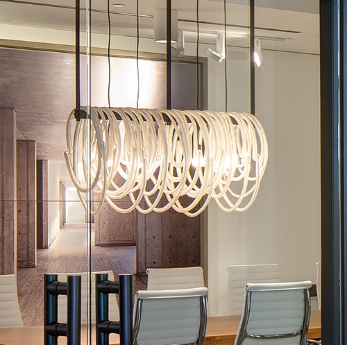 Large linear light fixture with glass loops of varying sizes.
