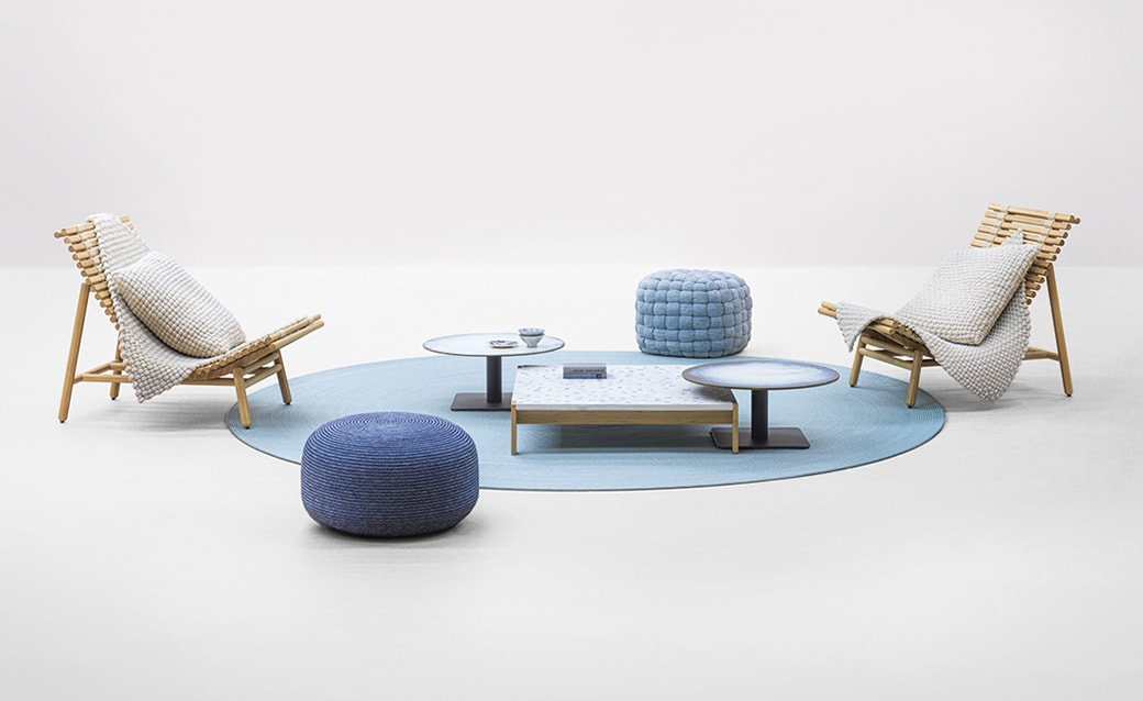 A minimalist and elegant living space featuring a blue-themed arrangement with contemporary seating, a central coffee table, and a soft circular rug, creating a serene and balanced aesthetic.