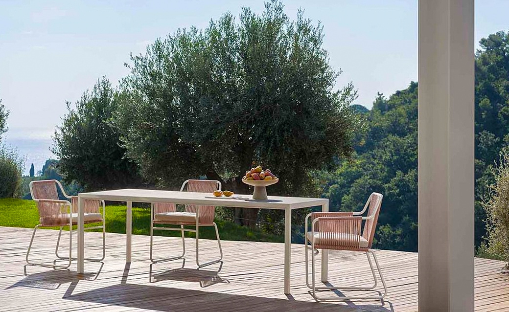 Elegant outdoor dining setup with a modern table and stylish chairs overlooking lush greenery