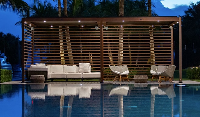 Tucci outdoor lounge area featuring a modern white sofa and matching chairs, reflecting in a tranquil pool