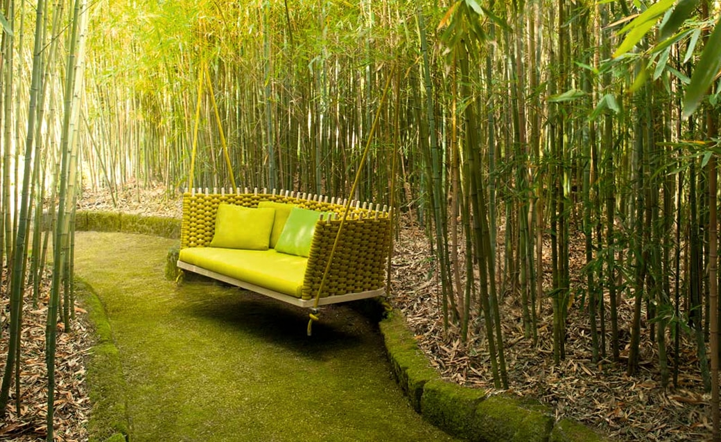 Shibui sofa with a woven frame and vibrant green cushions, nestled in a lush bamboo garden