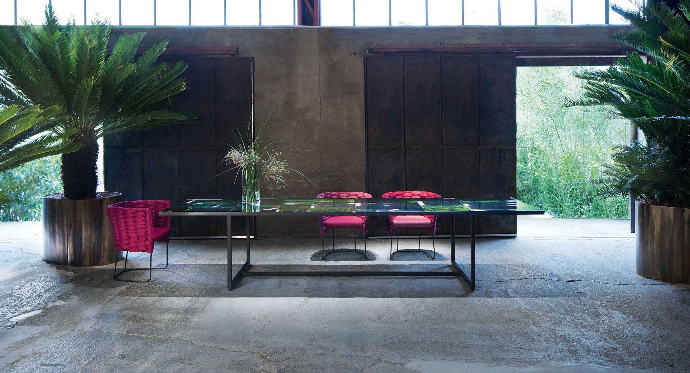 Sciari dining table with a sleek glass top and modern black frame, paired with vibrant red chairs