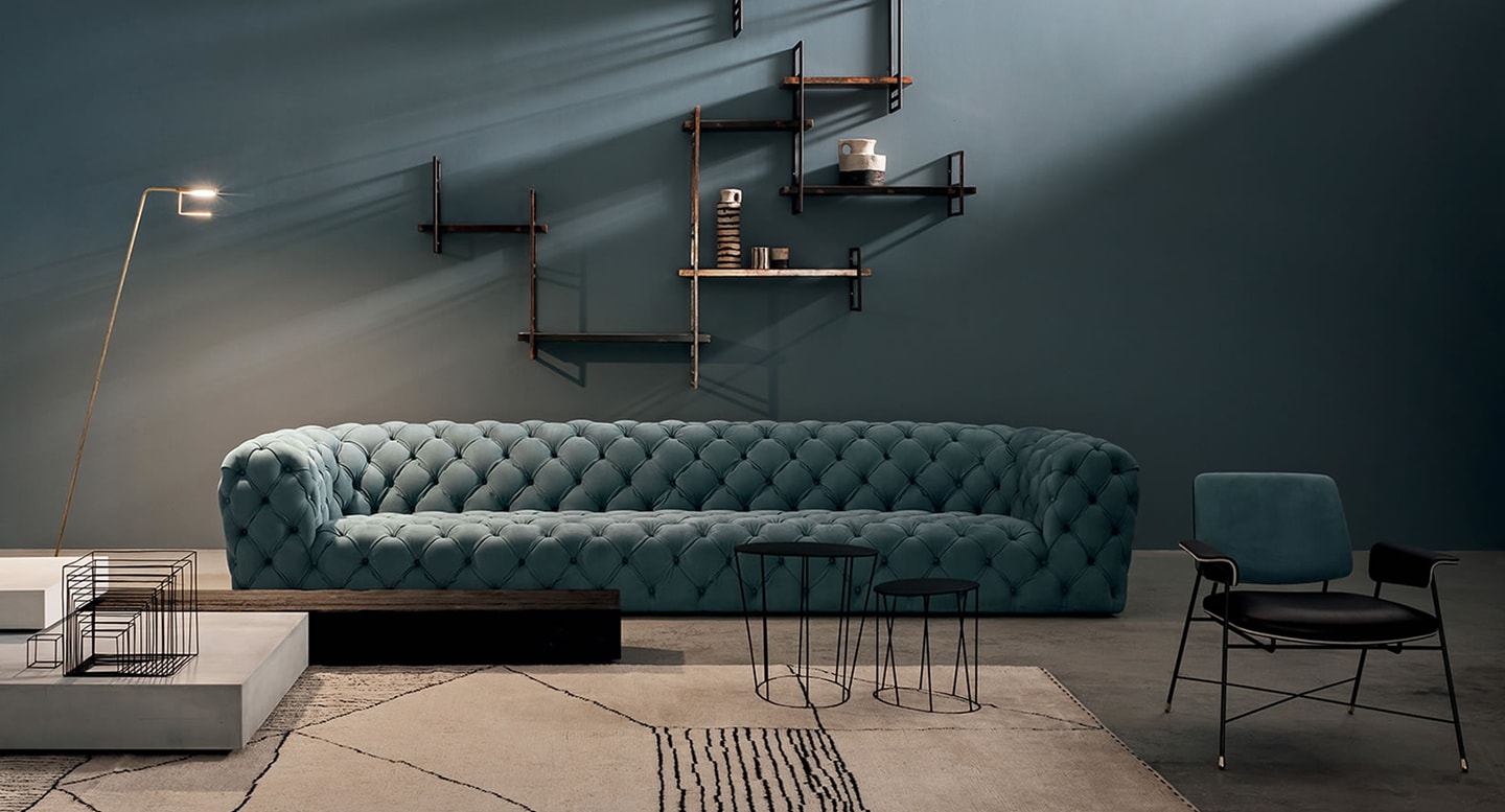 Chester Moon sofa with deep button tufting, luxurious upholstery, and an elongated silhouette against a dark, modern interior