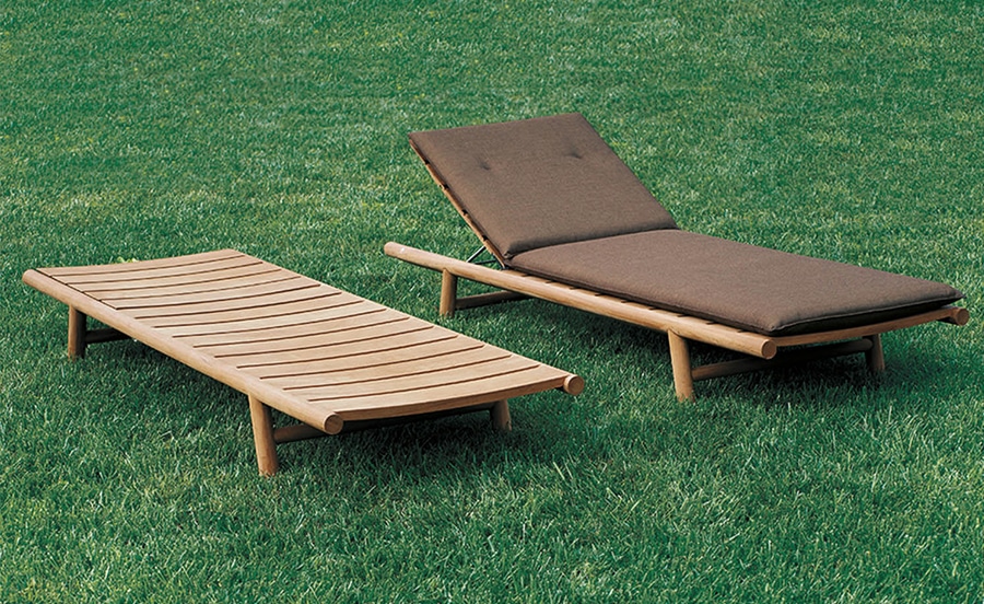 Orson Sun Lounger – A pair of elegant wooden outdoor loungers on a lush green lawn, one with a slatted design and the other featuring a brown cushioned backrest for comfort