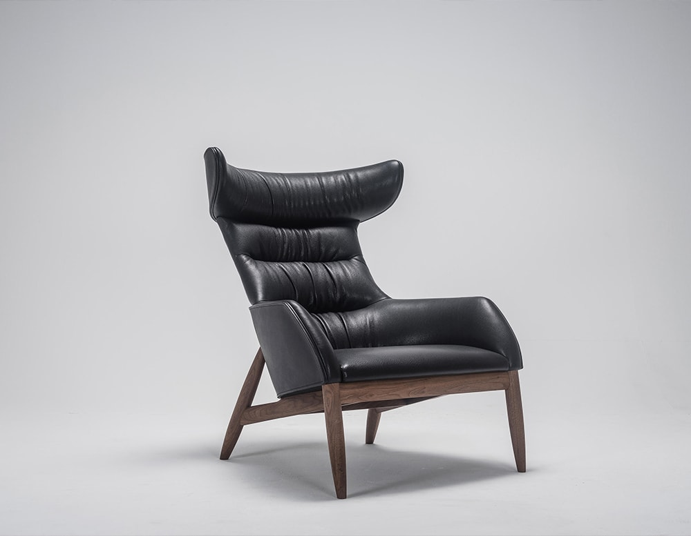 Armchair made of black leather with brown wooden base in a white background