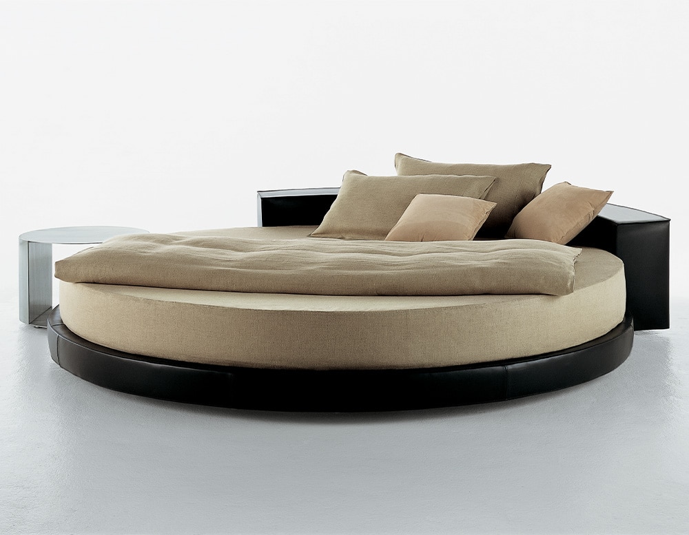 Circle-shaped bed made of black wood and light yellow fabric on a gray background