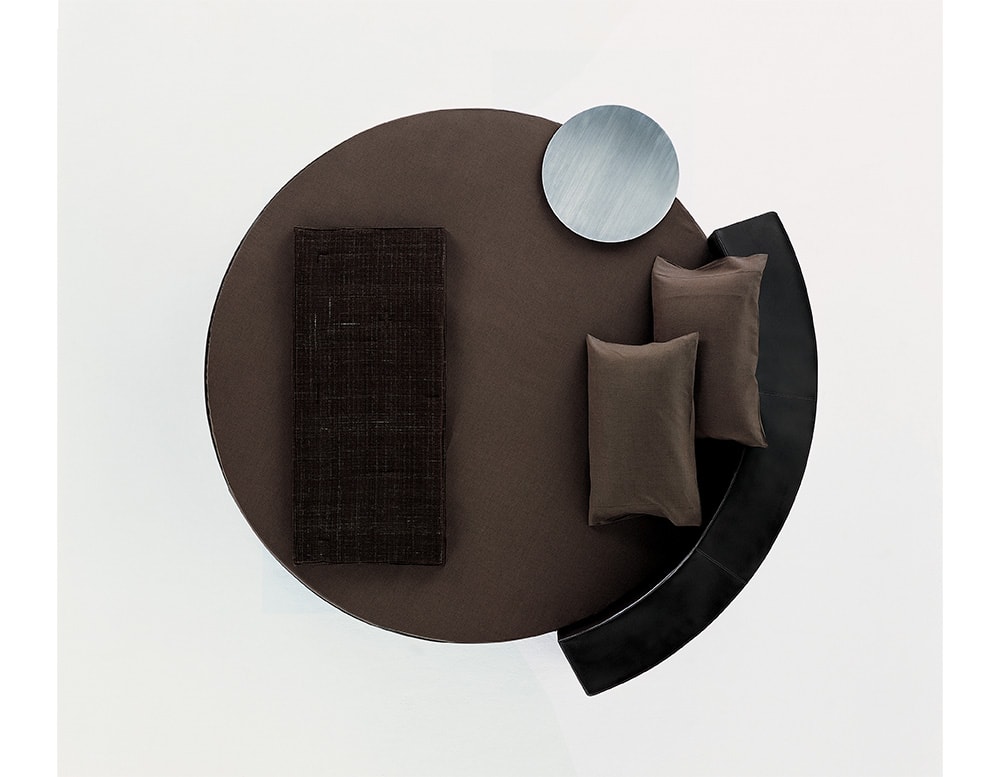 Dark brown bed in the shape of a circle with a black wooden backrest on a white background
