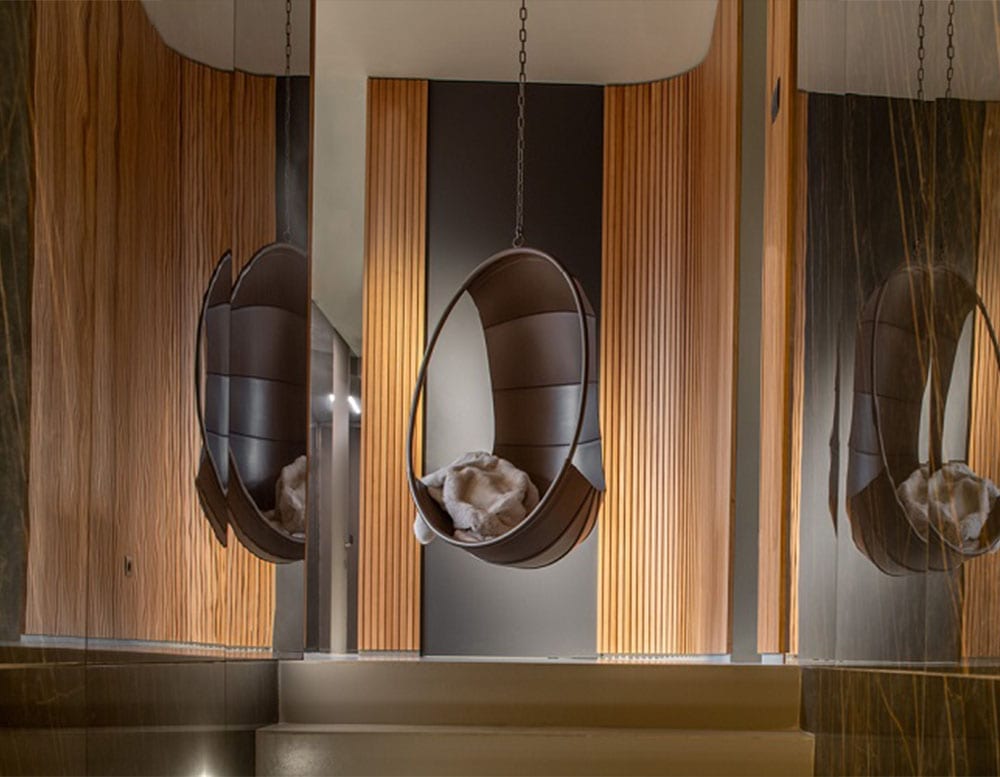 swing armchair made of dark brown leather throughout its structure and wrapped in mimoso of the same tone